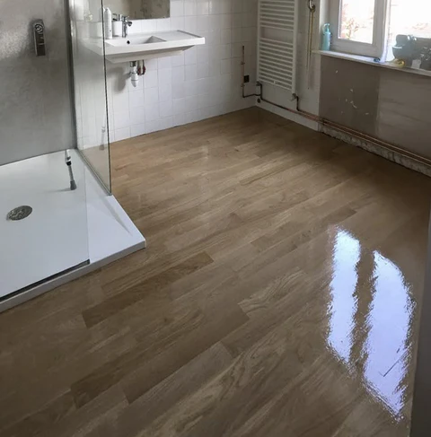 Salle de bain moderne en cours de rénovation avec sol en parquet flottant aspect bois fraîchement posé