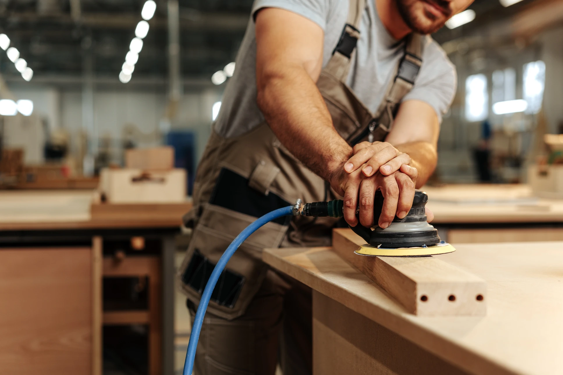 Artisan utilisant un rabot à main sur une planche de bois dans un atelier extérieur